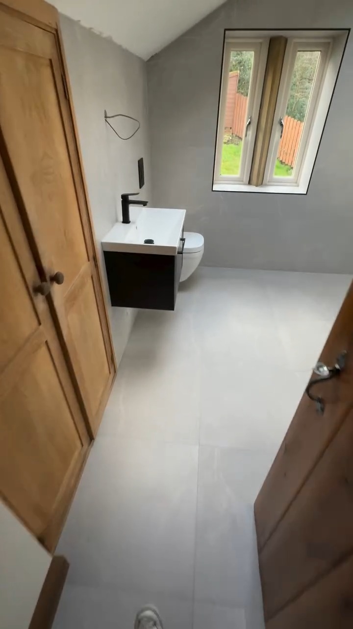 Walk-in shower and tiled bath in grey marble-effect tiles with black fittings