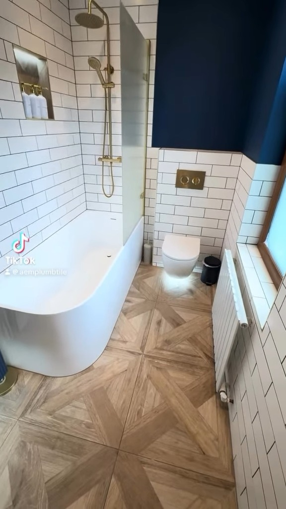Navy bathroom with gold shower, subway tiles and wood-effect floor